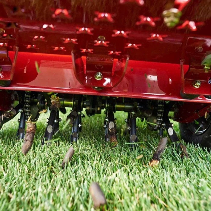 Lawn aerator with core tines pulling soil plugs from a green lawn